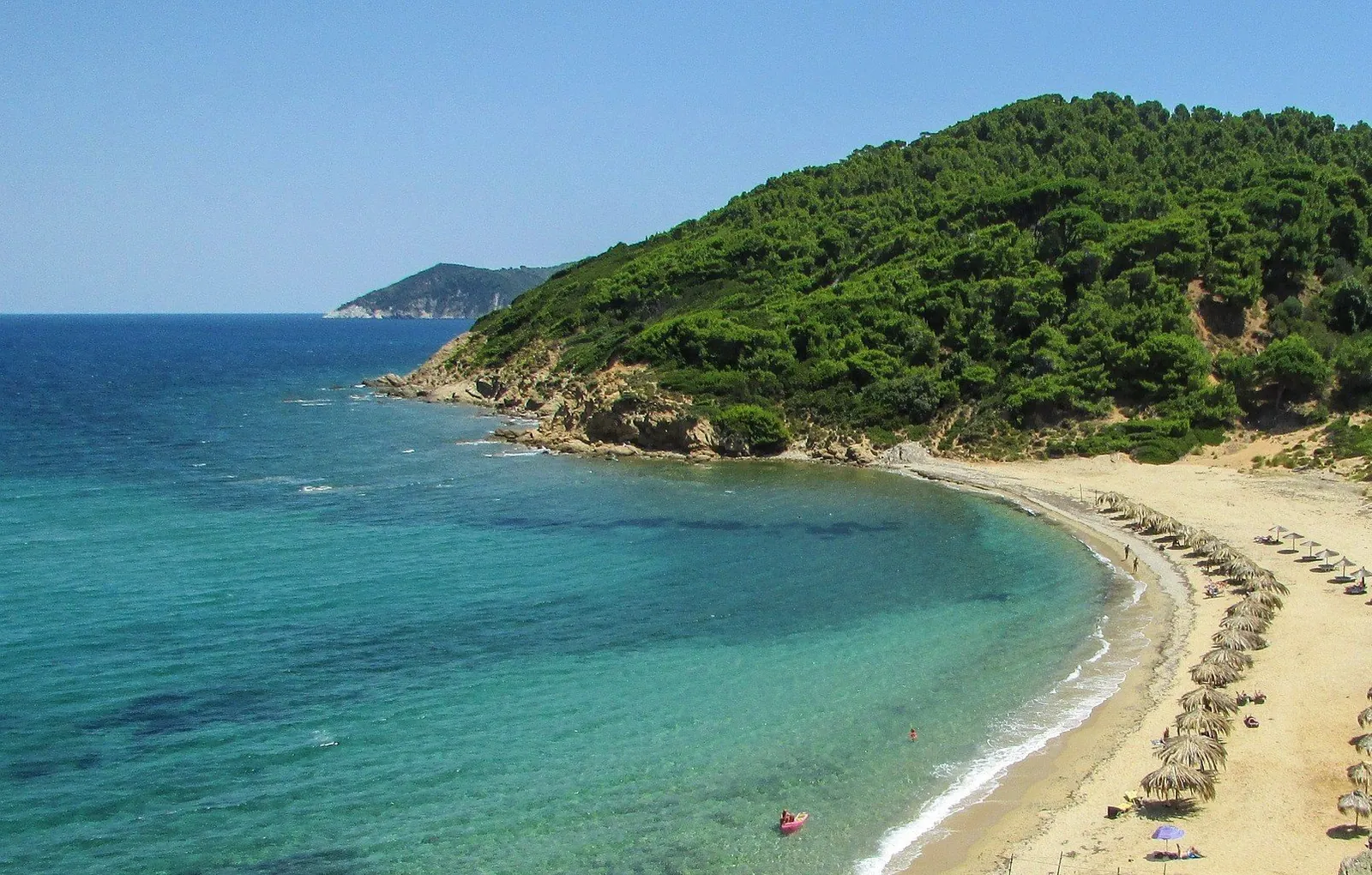 The sandy beach and pine-covered hills of Arkos